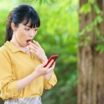 スマホを見て驚く若い女性