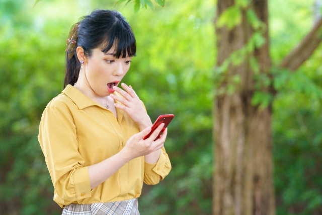 スマホを見て驚く若い女性